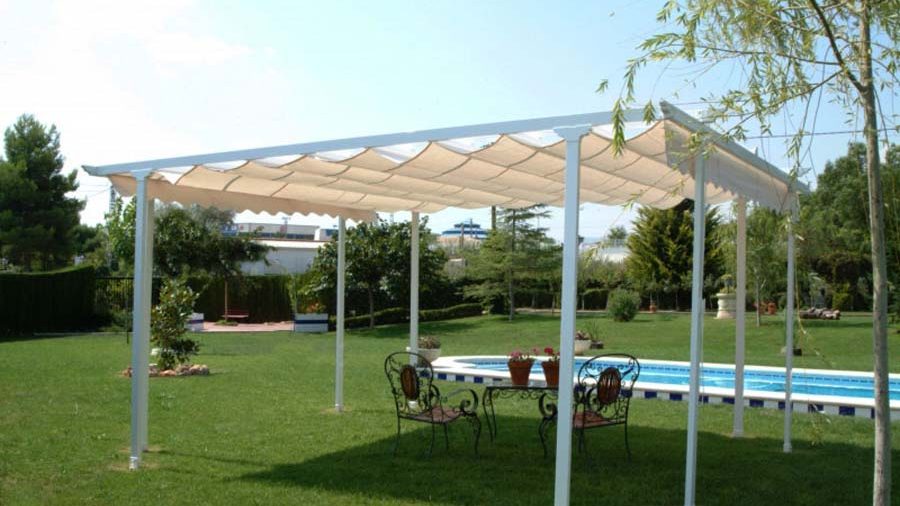 Pérgola con cubierta textil sobre el jardín y la piscina de una vivienda