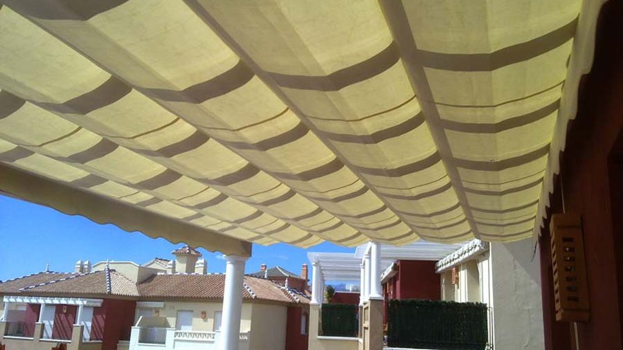 Toldo de palillería de rayas cubriendo un patio, visto desde el interior