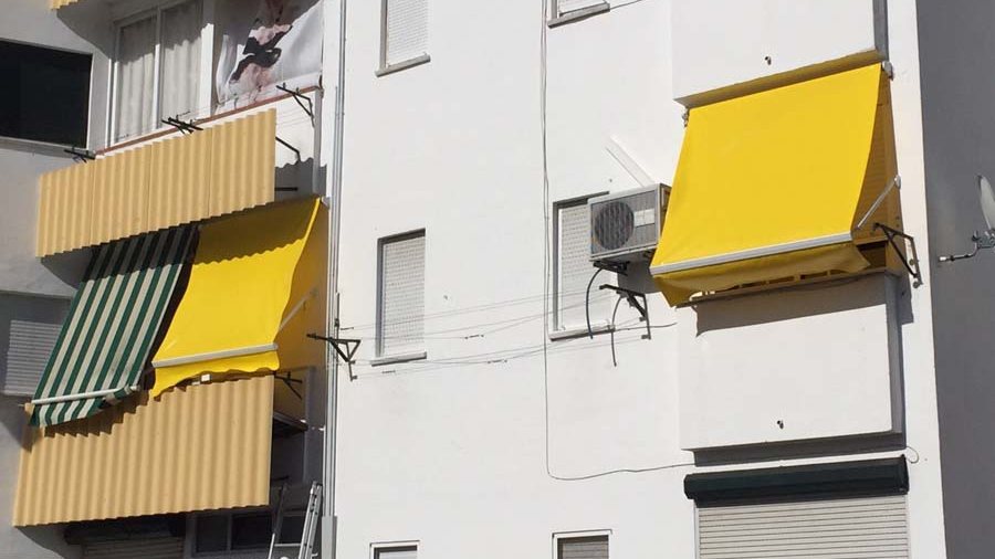 Toldos de punto recto amarillos instalados en los balcones de una fachada