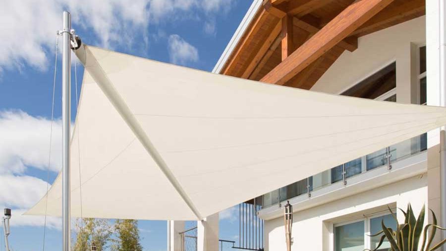 Toldos de vela triangulares tensados sobre el jardín de una vivienda